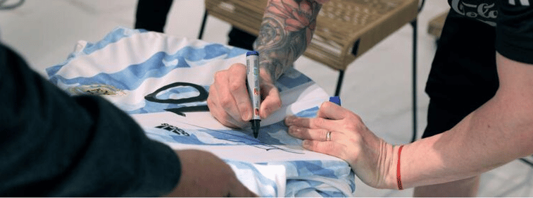 Football player signing a jersey during a private football player meet and greets